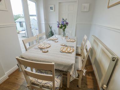 A dining room with a table and chairs at 16 Ffordd Meigan Beaumaris
