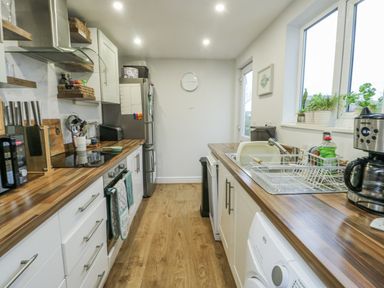 A kitchen with a sink and fridge at 16 Ffordd Meigan Beaumaris