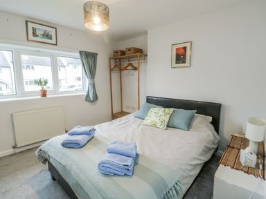 A bedroom with a bed and clothes rack at 16 Ffordd Meigan Beaumaris