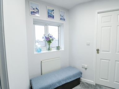 A hallway with a bench and flower vase at 16 Ffordd Meigan Beaumaris