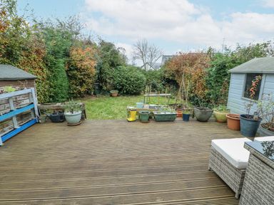 A garden with decking, planters, and a shed at 16 Ffordd Meigan Beaumaris