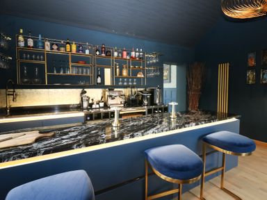 A kitchen with a bar, stools, and shelves at Chapel Hill in Catlowdy