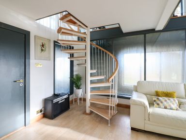 A living room with a spiral staircase and a sofa at Chapel Hill in Catlowdy