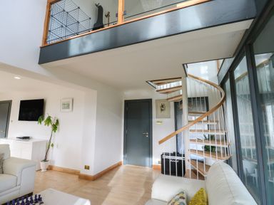 A living room with a staircase and television at Chapel Hill in Catlowdy