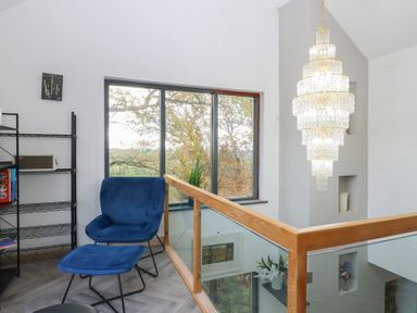 A landing area with a blue chair and chandelier at Chapel Hill in Catlowdy