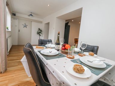 A dining room with a table set for meals at Long Barn in Burton Bradstock