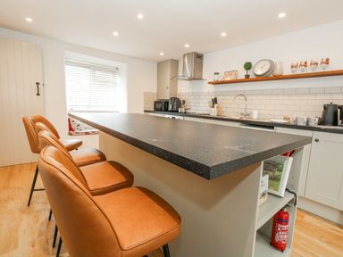 A kitchen with a bar island and appliances at Long Barn in Burton Bradstock