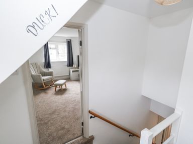 A staircase leading to a landing with a rocking chair and table at Long Barn in Burton Bradstock