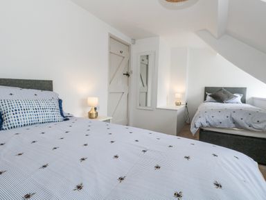 A bedroom with two beds and a lamp at Long Barn in Burton Bradstock