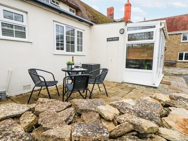 An outdoor seating area with a table and chairs at Long Barn in Burton Bradstock