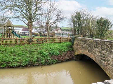 A playground with a slide and a bridge over water at Long Barn in Burton Bradstock