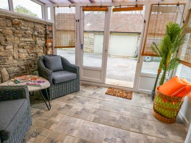 A conservatory with chairs and a table at Long Barn in Burton Bradstock