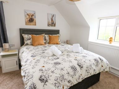 A bedroom featuring a double bed with floral bedding at Long Barn in Burton Bradstock