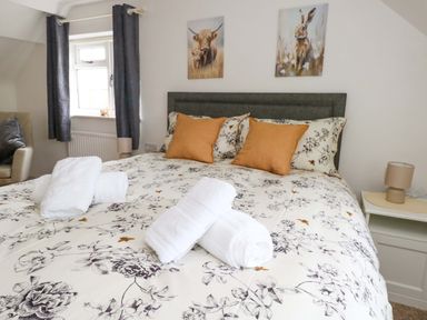 A bedroom with a double bed and artwork on the walls at Long Barn in Burton Bradstock