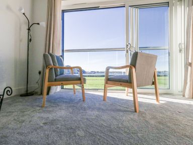A living room with two armchairs and a sliding door at Seafern House 36B in Poole