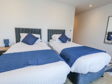 A bedroom with two beds and a bedside table at Seafern House 36B in Poole