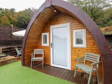 An outdoor area with wooden pod structure and seating at Cwtch Bach Aberdare