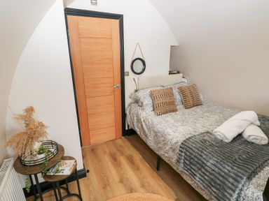 A bedroom with a bed, table, and door at Cwtch Bach in Aberdare