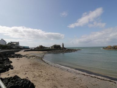 A beach with a lighthouse and buildings at Peaceful in Stranraer