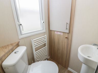 A bathroom with a toilet, sink, and radiator at Peaceful in Stranraer