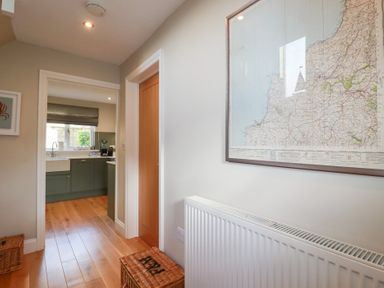 A hallway with a map on the wall and a view of the kitchen at The Mizzen in St Endellion near Port Isaac