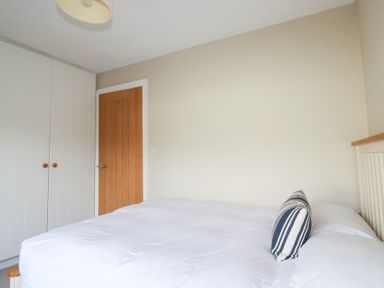 A bedroom with a bed and a wardrobe at The Mizzen in St Endellion near Port Isaac