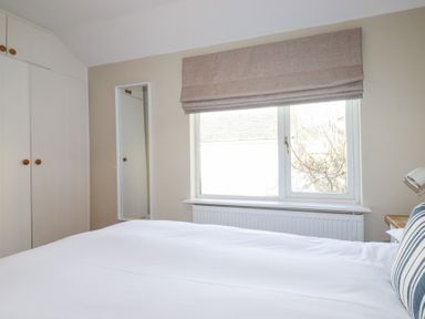 A bedroom with a wardrobe and a window at The Mizzen in St Endellion near Port Isaac