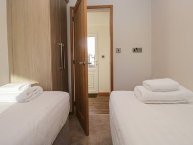 A bedroom with twin beds and a wardrobe at Bluebell Lodge in Warton