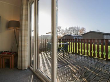 A living room with sliding doors leading to a deck at Bluebell Lodge Warton