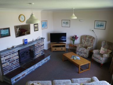 A living room with a television and fireplace at Badgers Cliff in Polzeath