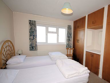 A bedroom with two beds and a chair at Badgers Cliff in Polzeath