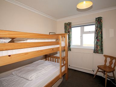 A bedroom with a bunk bed and a single bed at Badgers Cliff in Polzeath