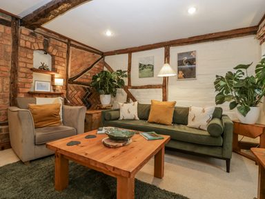 A living room with a sofa and armchair at Magpie Cottage in Worcester