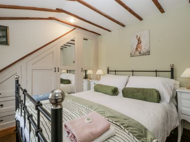 A bedroom with a bed and nightstands at Magpie Cottage in Worcester