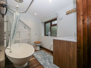 A bathroom with a bath tub, toilet, and sink at Magpie Cottage Worcester