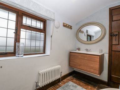 A bathroom with a sink and mirror at Magpie Cottage in Worcester