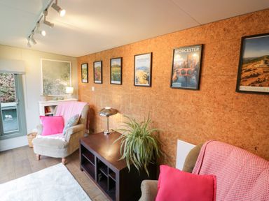 A sitting room with posters on the wall and a plant at Magpie Cottage, Powick near Callow End