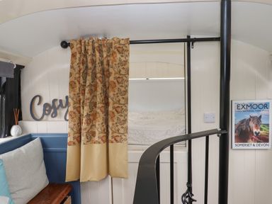 A sleeping area with a sofa and spiral staircase at The Bus on the Hill