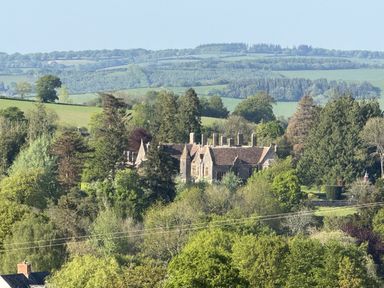 A mansion surrounded by trees and fields at The Bus on the Hill in Huntsham near Bampton, Devon