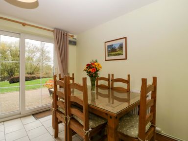 A dining room with a table and chairs at Orchard Cottage Corse near Gloucester