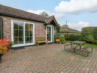 An outdoor patio area with a table and bench at Orchard Cottage in Corse near Gloucester