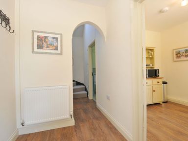 A hallway with a painting and a microwave in the cupboard at Copper Mine Cottage Trelill near Port Isaac