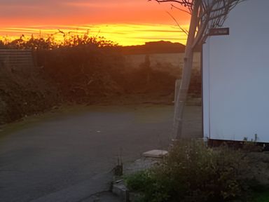 A view of a sunset with a tree and road at The Nook in 