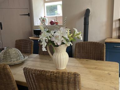 A kitchen with a table and vases of flowers at High Dyke Cottage