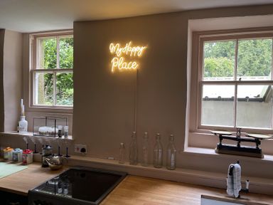 A kitchen with a neon sign and bottles at High Dyke Cottage