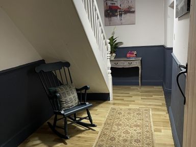 A hallway with a rocking chair and a small table at High Dyke Cottage