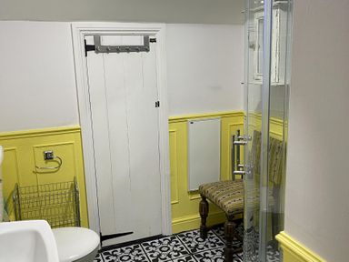 A bathroom with a toilet, shower, and chair at High Dyke Cottage