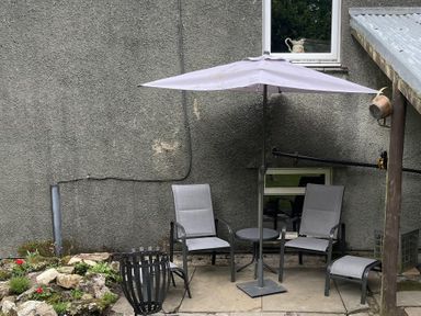 An outdoor seating area with chairs and an umbrella at High Dyke Cottage