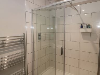 A shower enclosure with glass doors and towels in a bathroom at ASH HOUSE