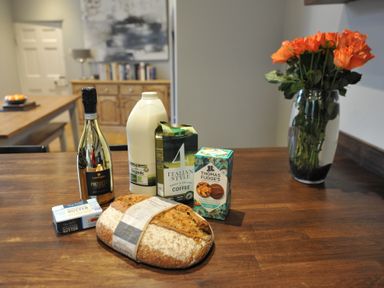 A kitchen table with prosecco, milk, coffee, biscuits, and bread at ASH HOUSE in Wincanton